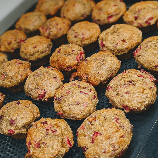 Mini cranberry muffins displayed on a surface, showing their small round shape and cranberry-studded tops