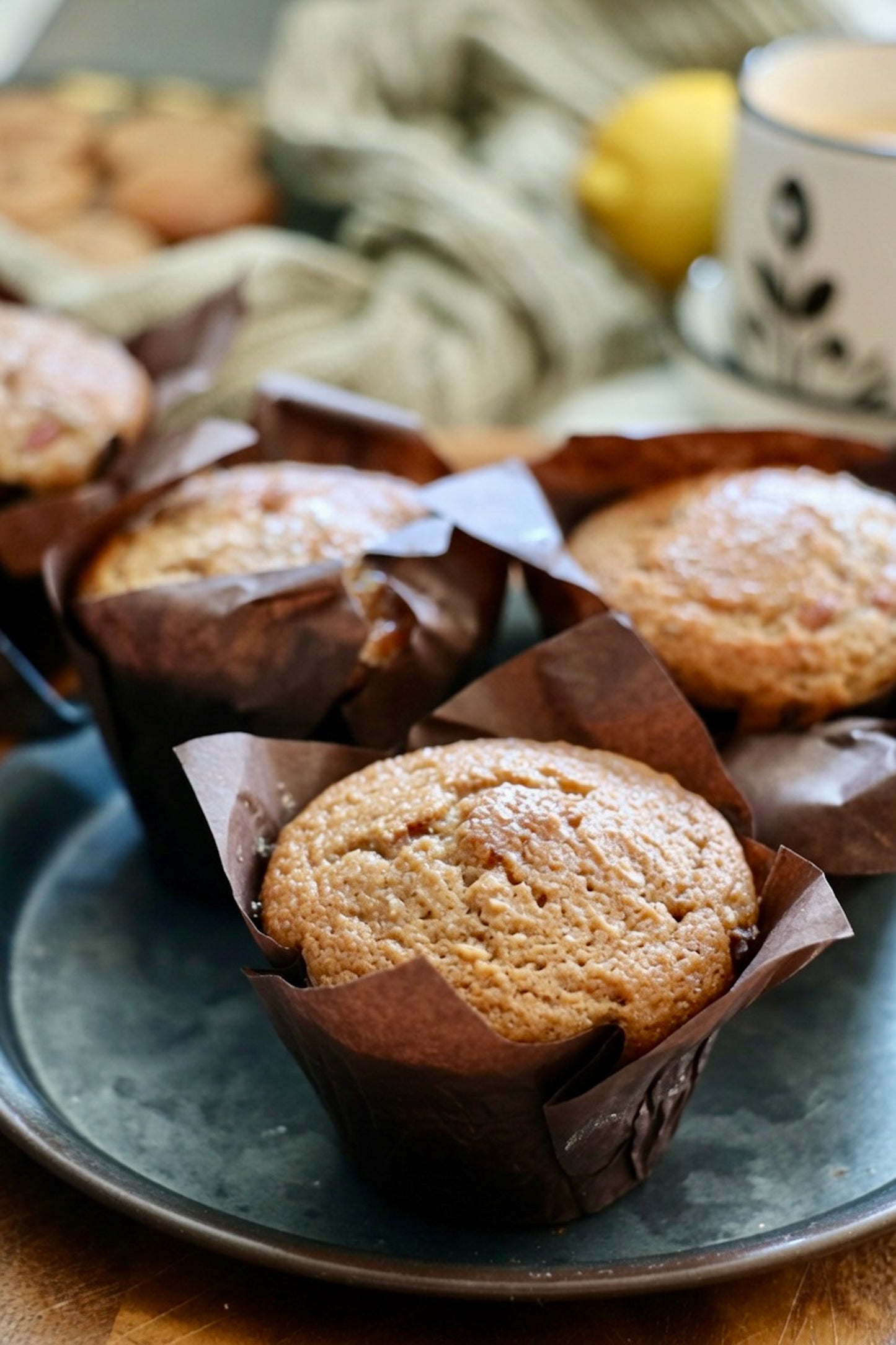 Whole wheat lemony strawberry muffins in brown parchment wrappers on a blue plate, clean-label and nutritious Canadian.