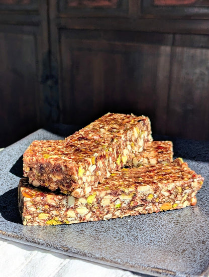 Three stacked cranberry protein bars with visible oats and seeds on a dark plate, showcasing clean-label, no refined sugar,.