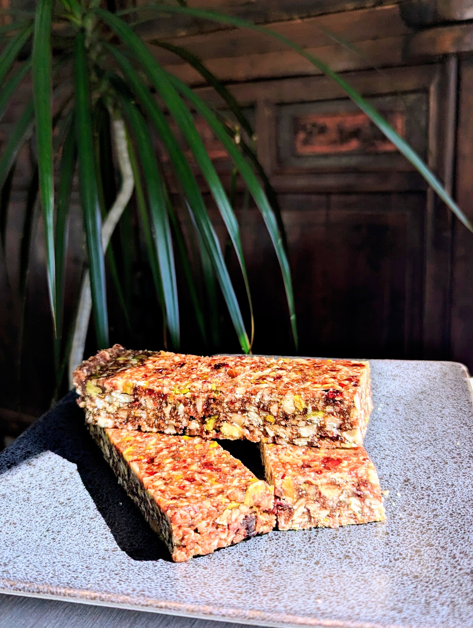 Two stacked cranberry booster protein bars with visible cranberries and oats on a ceramic plate, showcasing nutritious,.